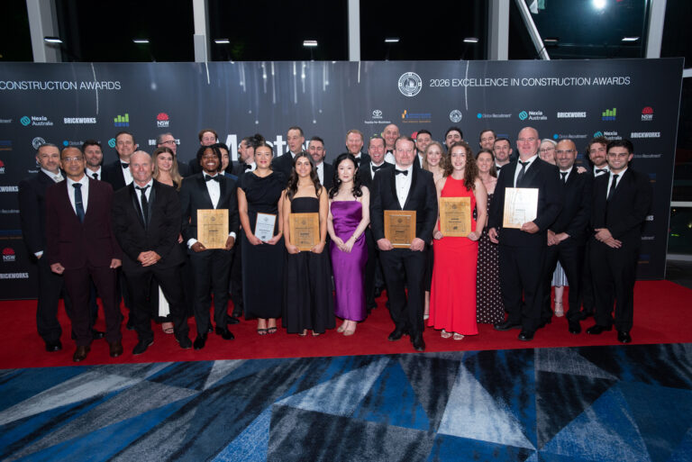 Group of award winners holding plaques on the red carpet at the 2026 Excellence in Construction Awards